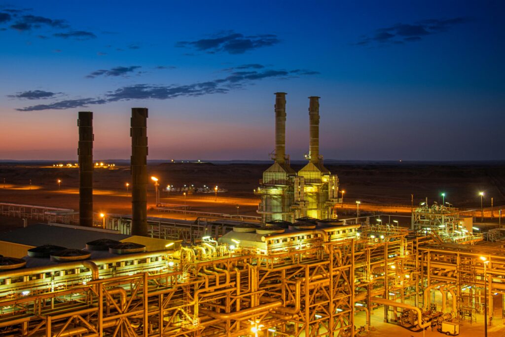 Aerial view of illuminated industrial power plant with chimneys at sunset, representing energy production infrastructure
