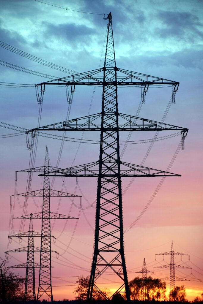 Electricity pylons silhouetted against a dramatic sunset sky, illustrating high voltage transmission infrastructure